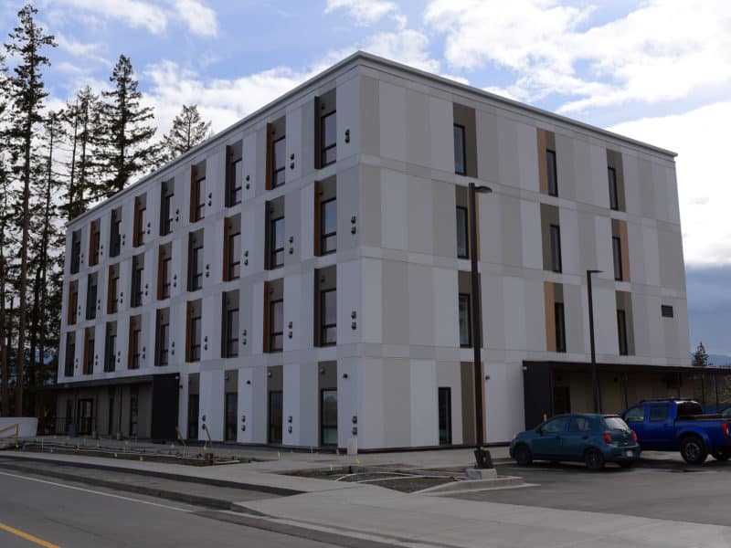 A photo of the supportive housing building on Paddle Road. It is square, grey and has rows of windows all around.