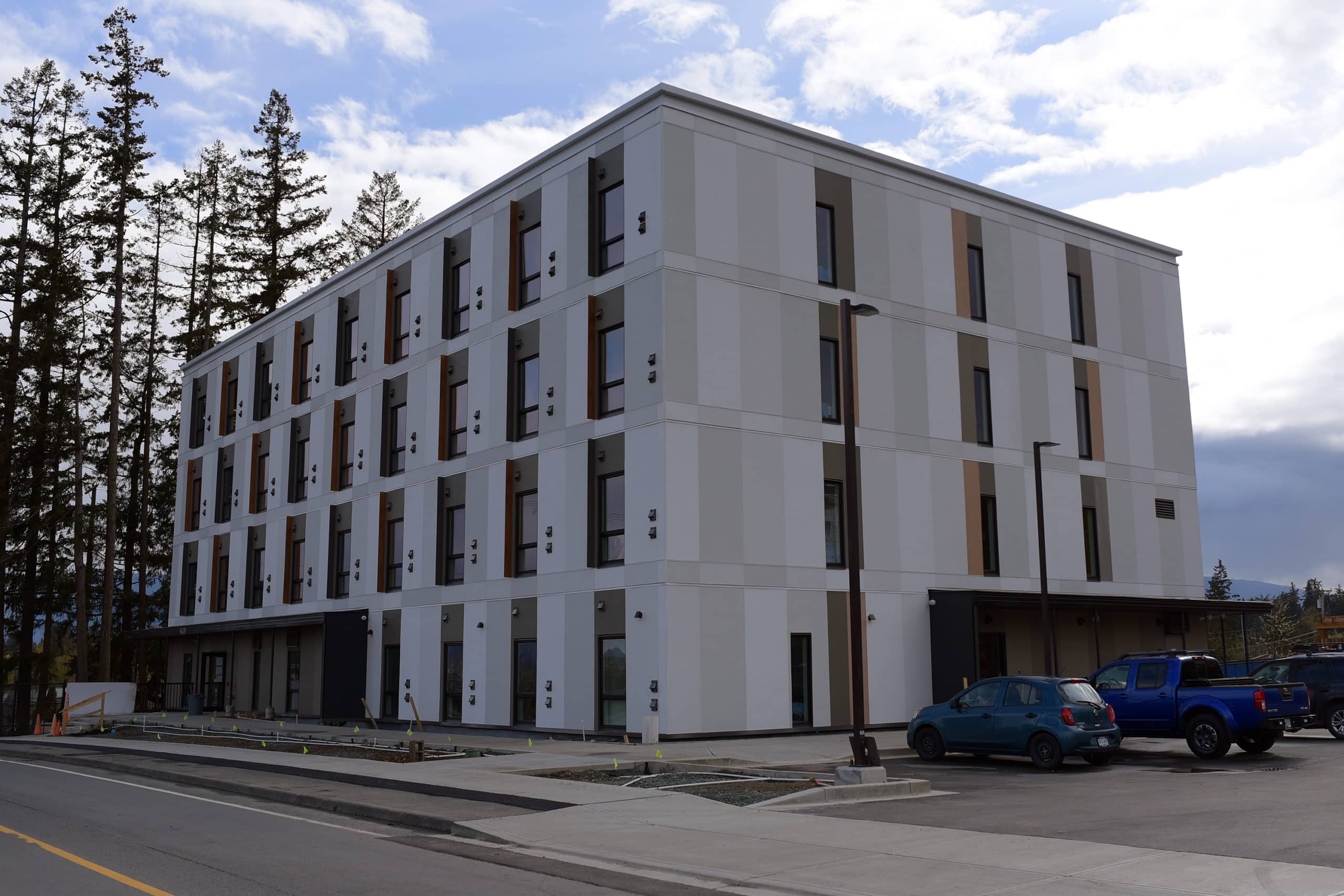 A photo of the supportive housing building on Paddle Road. It is square, grey and has rows of windows all around.