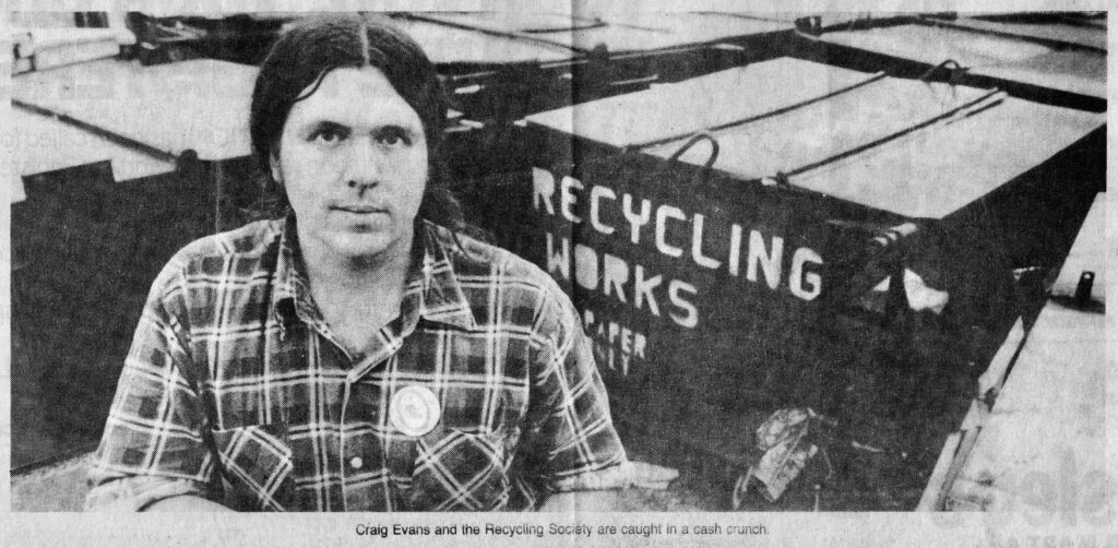 A news article photo of a young Craig Evans standing in front of large recycling bins.