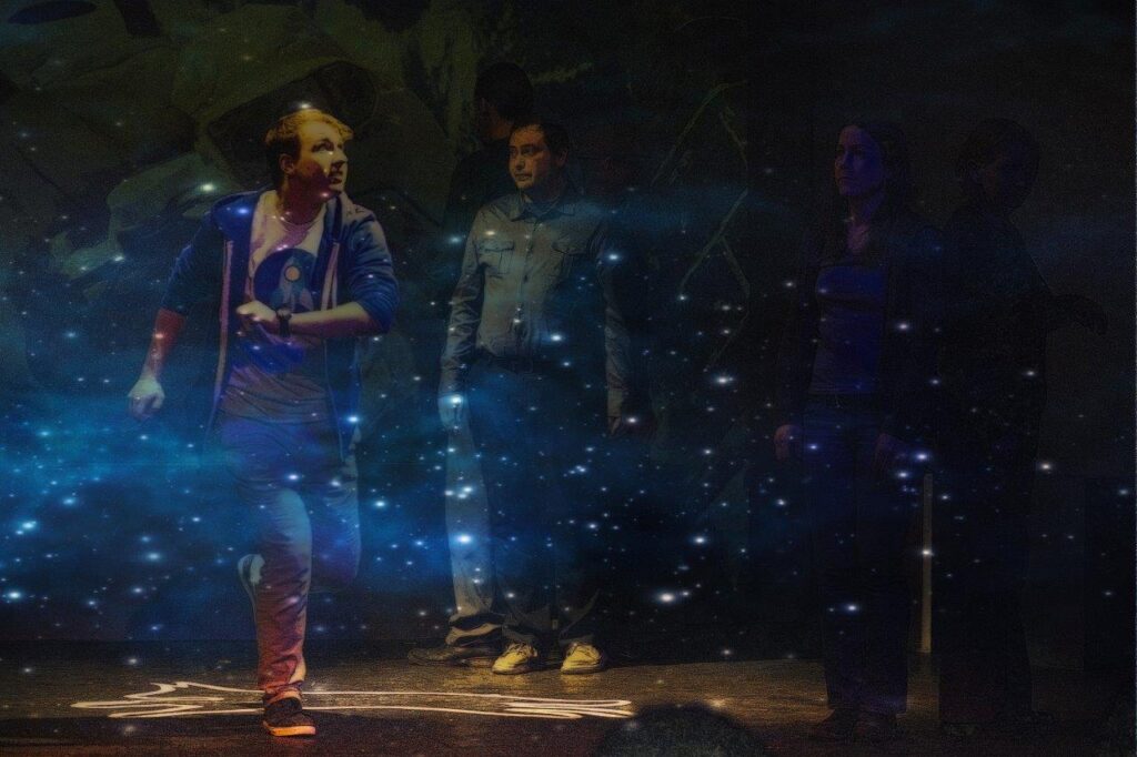 An image of a stageplay with two individuals on stage surrounded by what seems to be ethereal-looking stars suspended in space and fog.