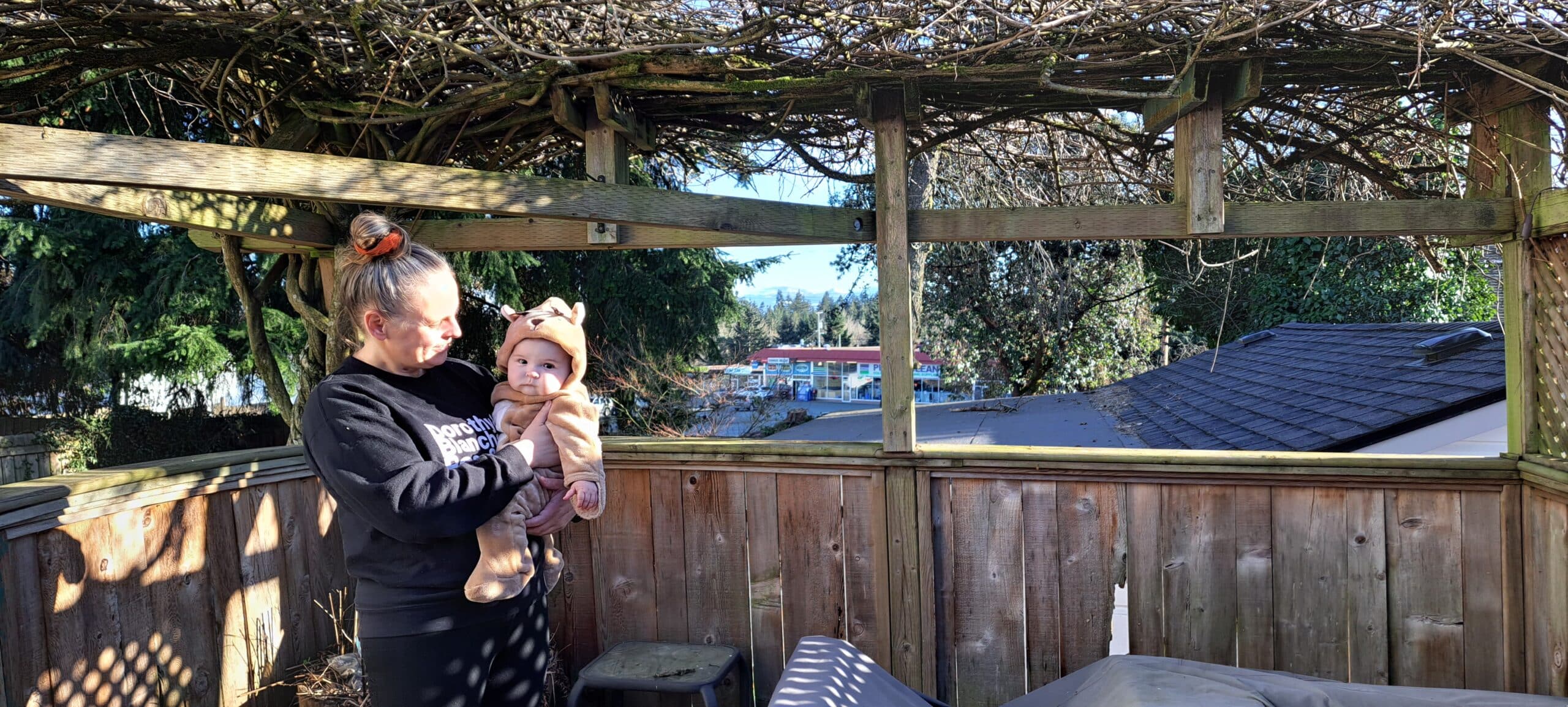 Danielle Baker and her baby on home porch in front of where abandoned building once stood.