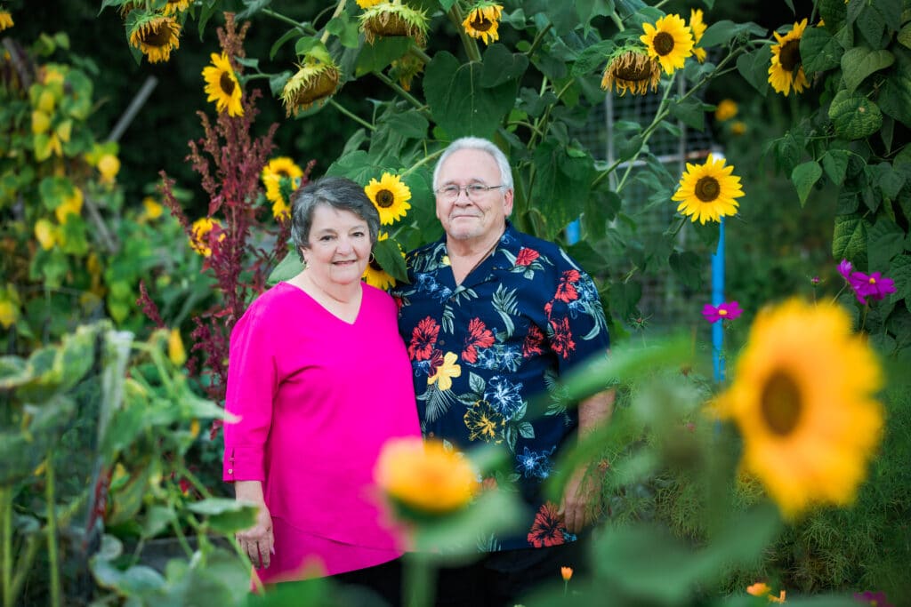 An older couple surrounded by sunflowers.