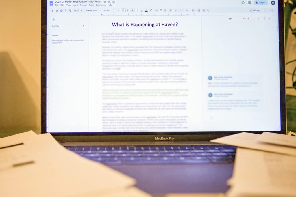 A computer displays a draft document with text blurred out and the words "What's happening at Haven?"