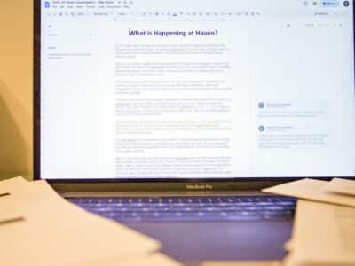 A computer displays a draft document with text blurred out and the words "What's happening at Haven?"