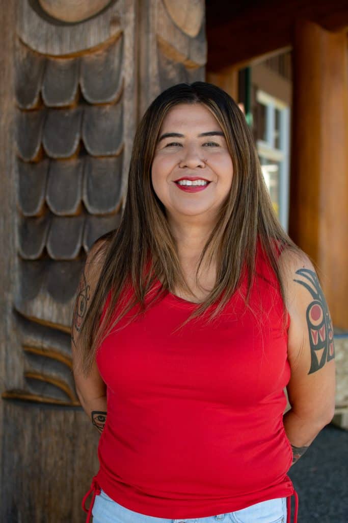 A photo of Emmy Manson, from waist up, smiling and facing the camera.