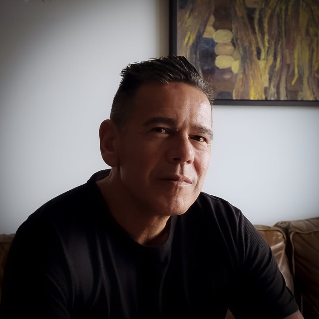 Taiaiake Alfred gazes at the camera with a thoughtful smile, light shining on the right side of his face.