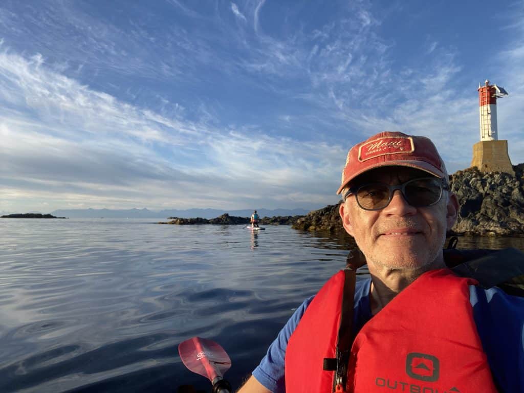 A man in a red ball cap and red lifejacket sits in a kayak on the water