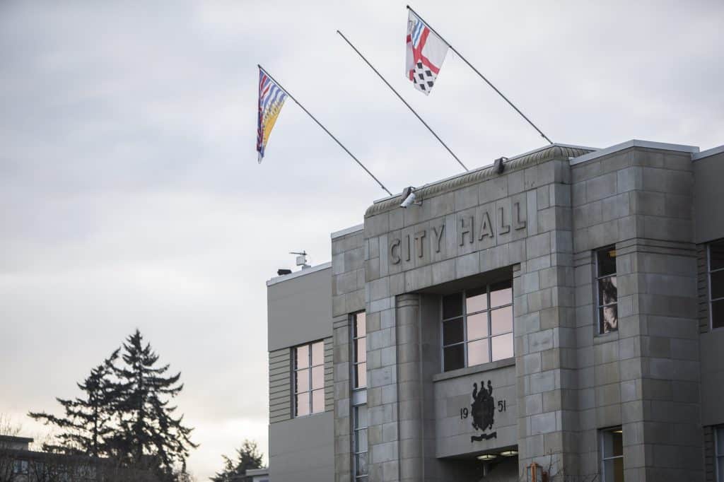 Image of Nanaimo's City Hall, grey building with flag poles and sign reading City Hall
