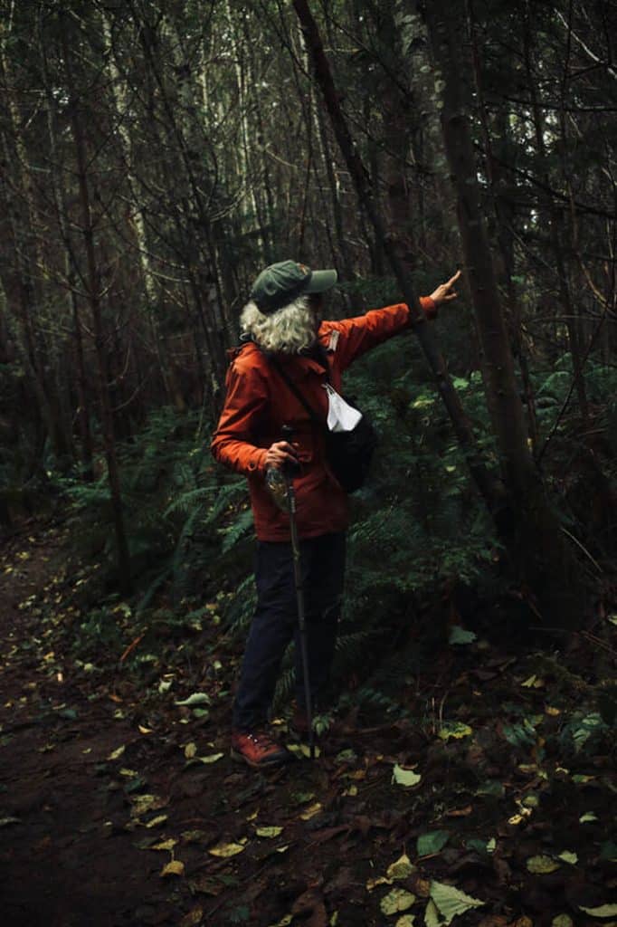 A grey-haired woman points at some lichen she found in the Cumberland Forest