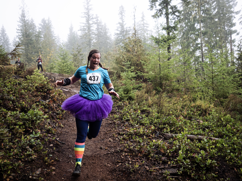 A runner in a tutu runs along a misty trail
