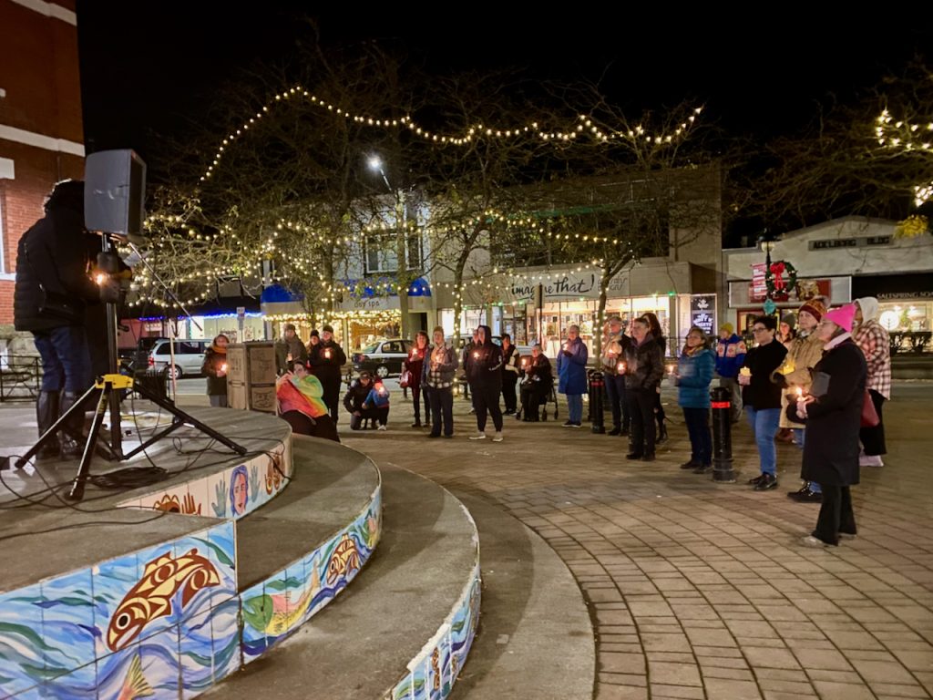A crowd gathers in front of a stage, holding candles