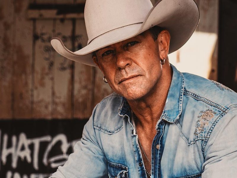 Aaron Pritchett, a man in his 50s, is tanned and wearing a white cowboy hat and worn blue jean shirt