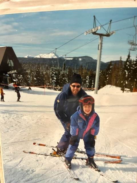 Young child skiing with their dad