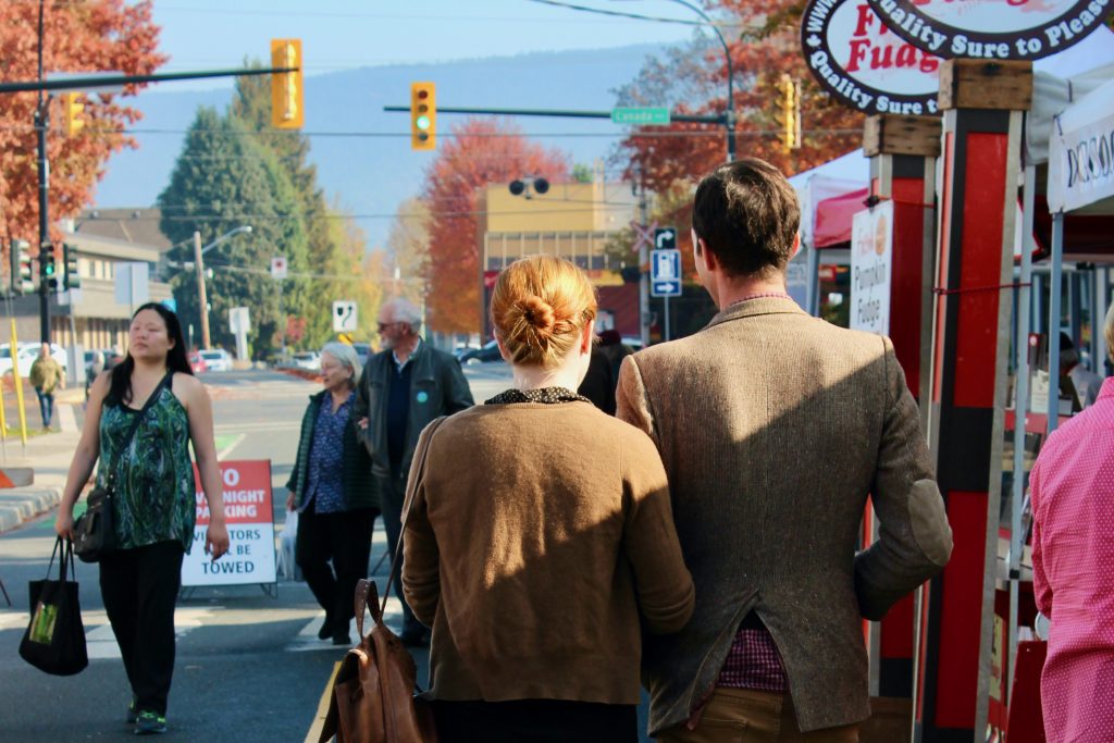 A couple and other other people in the background are seen from behind walking through the market.