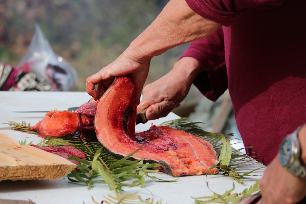 A close-up of T’awahwiye (Philomena Williams) cutting into the salmon.