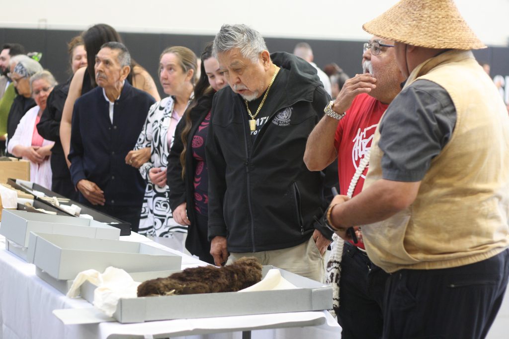 A line of Snuneymuxw First Nation members view artifacts on a table