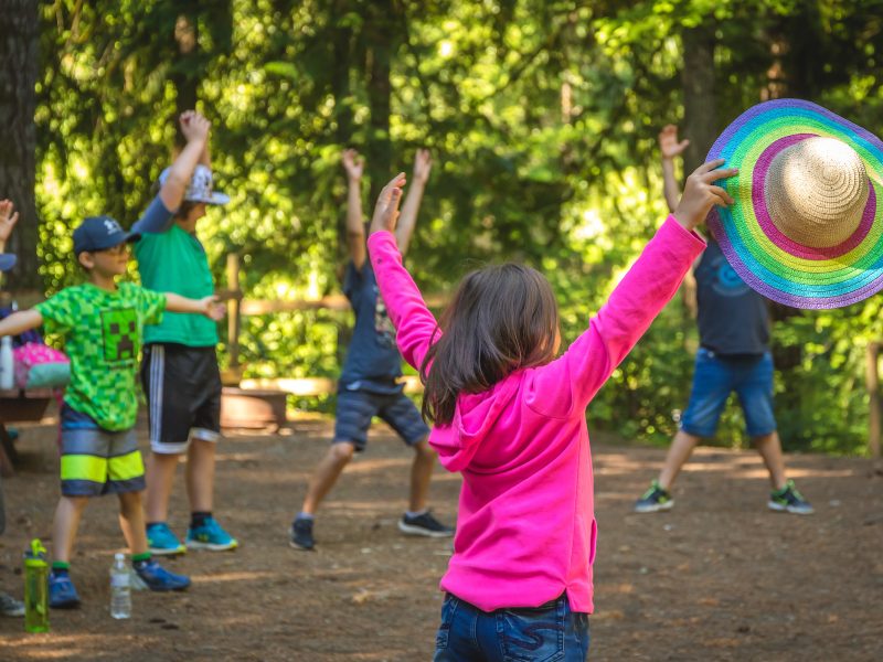 Children in forest, one holds a rainbow hat