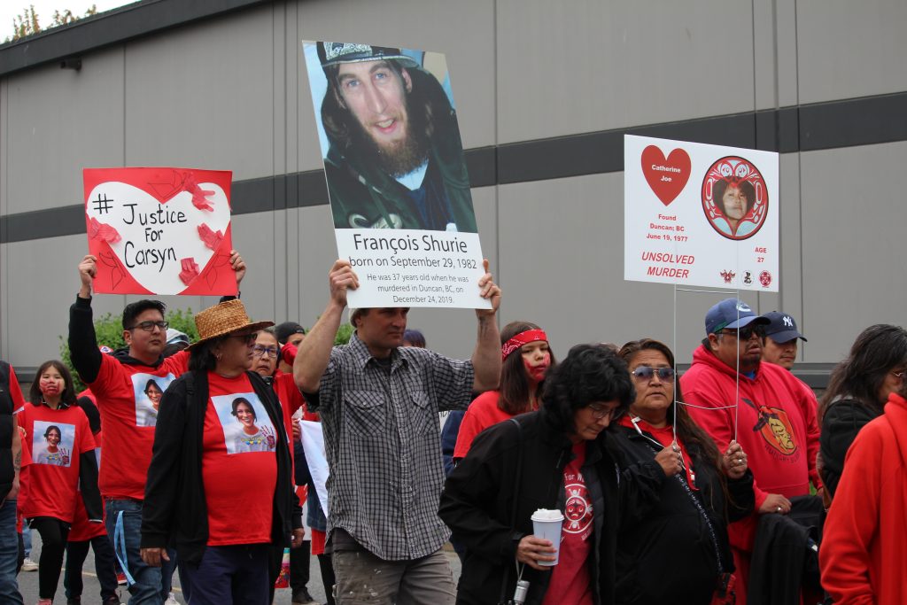 People march and carry signs with names and photos of loved ones who are missing and murdered.