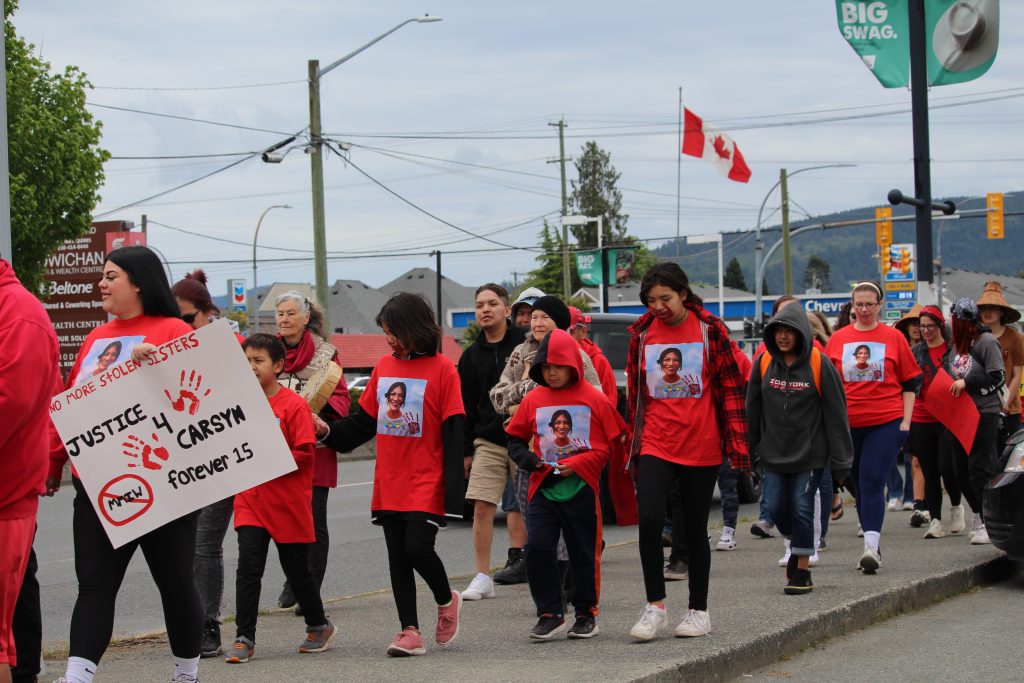 People march wearing red t-shirts that have a portrait of Carsyn Mackenzie Seaweed on it.