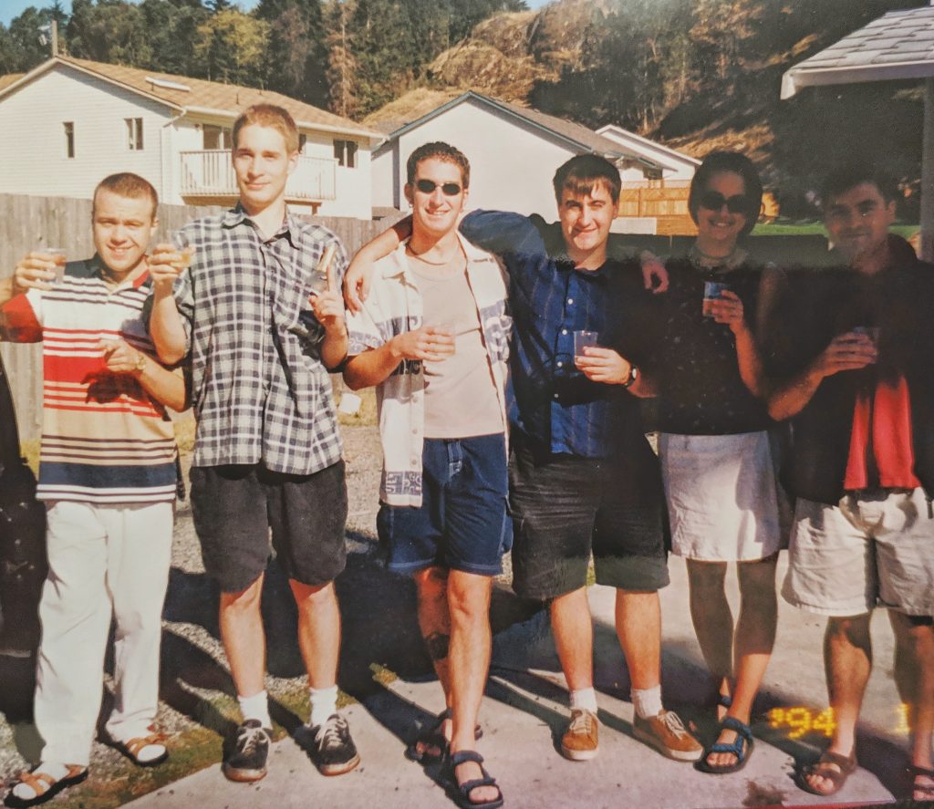 A group in a 90s era photo stand with shot glasses