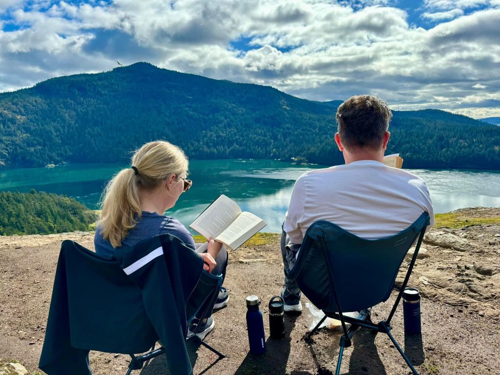 Jordan and his pictured from behind. They're sitting in lawn chairs and reading atop Stoney Hill facing the ocean.