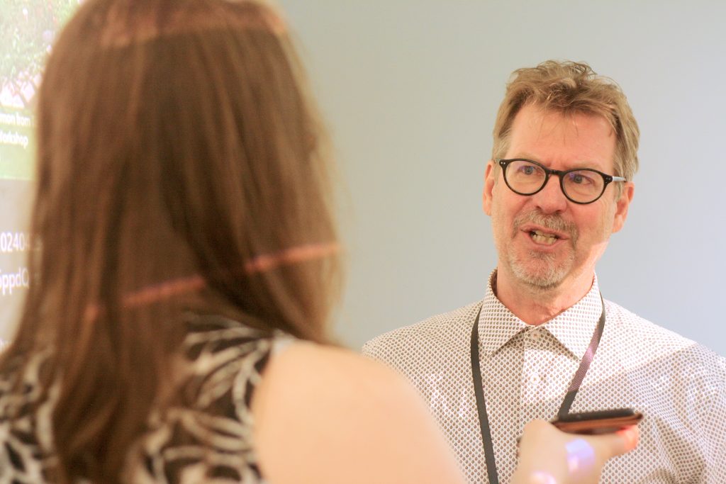 A man in glasses is interviewed by a woman with her back to the camera