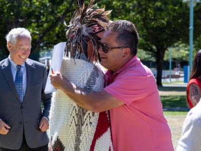 Bill Yoachim, in pink shirt and sunglasses, embraces Chief Wyse in regalia and blanket