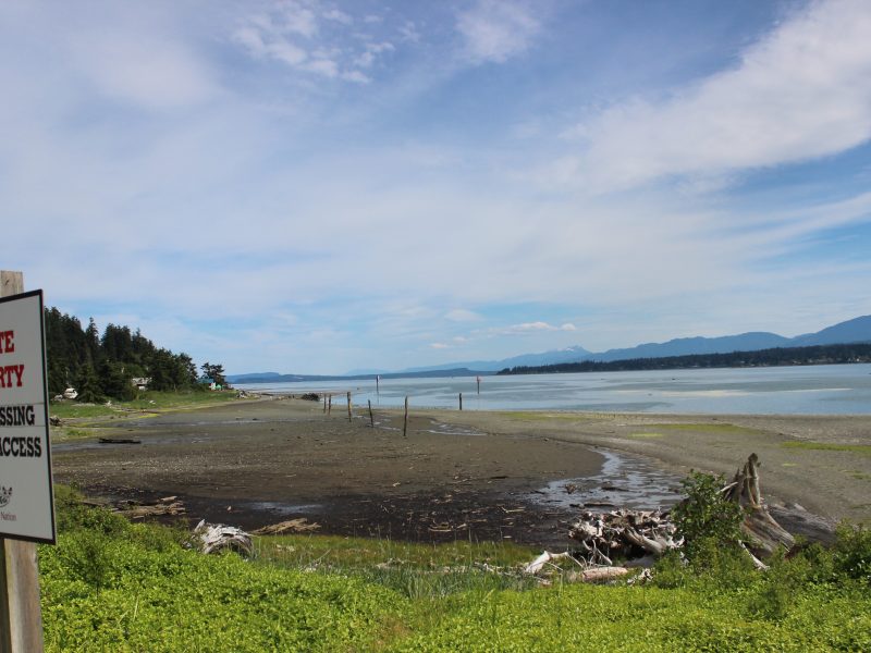 A sign with the K'ómoks First Nation Logo in the foreground reads "Private property. No trespassing, no beach access." K'ómoks First Nation was one of the nations involved in the creation of the BC First Nation spill alert.