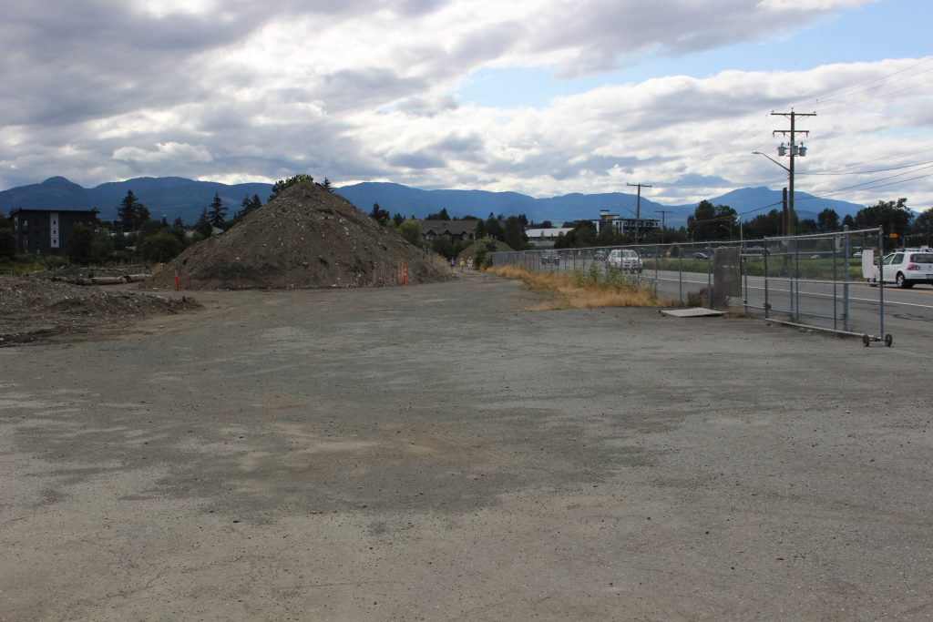A mostly empty lot with concrete and a large pile of dirt in the background.