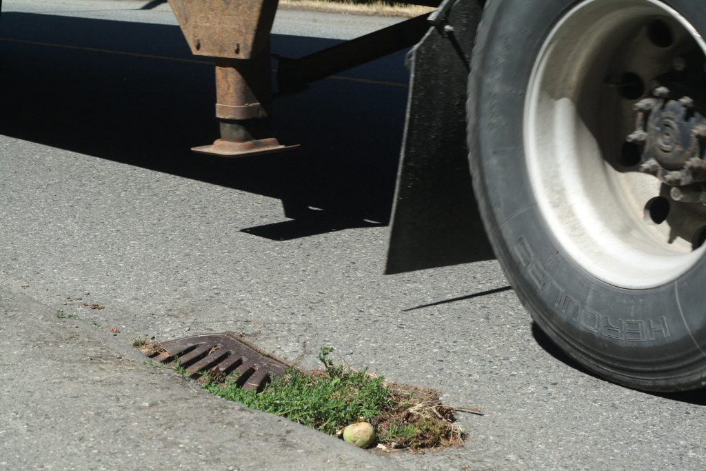A truck tire drives past a storm drain