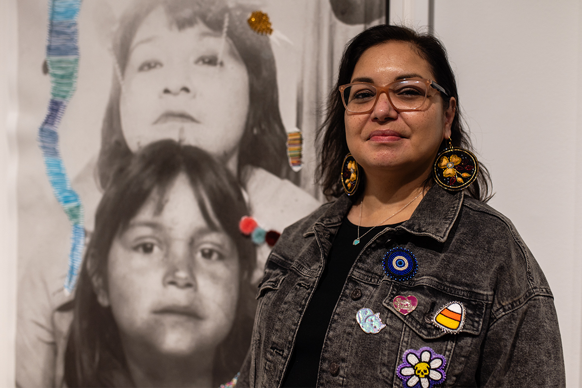 Cree artist Michelle Sound stands in front of a photograph of her as a shield with her mother at a Nanaimo Art Gallery exhibit also featuring works from Snuneymuxw artist Eliot White-Hill, Kwulasultun. Photo by Mick Sweetman / The Discourse.