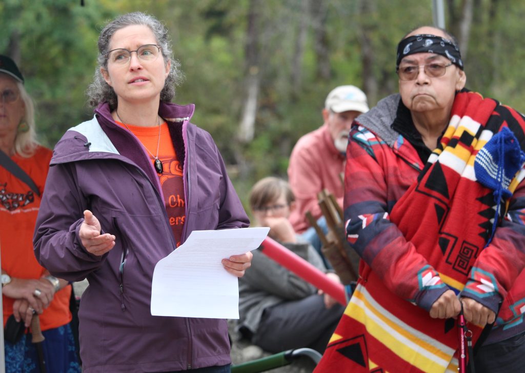 Jennifer Shepherd speaking with paper in hand and Elder John George standing next to her.
